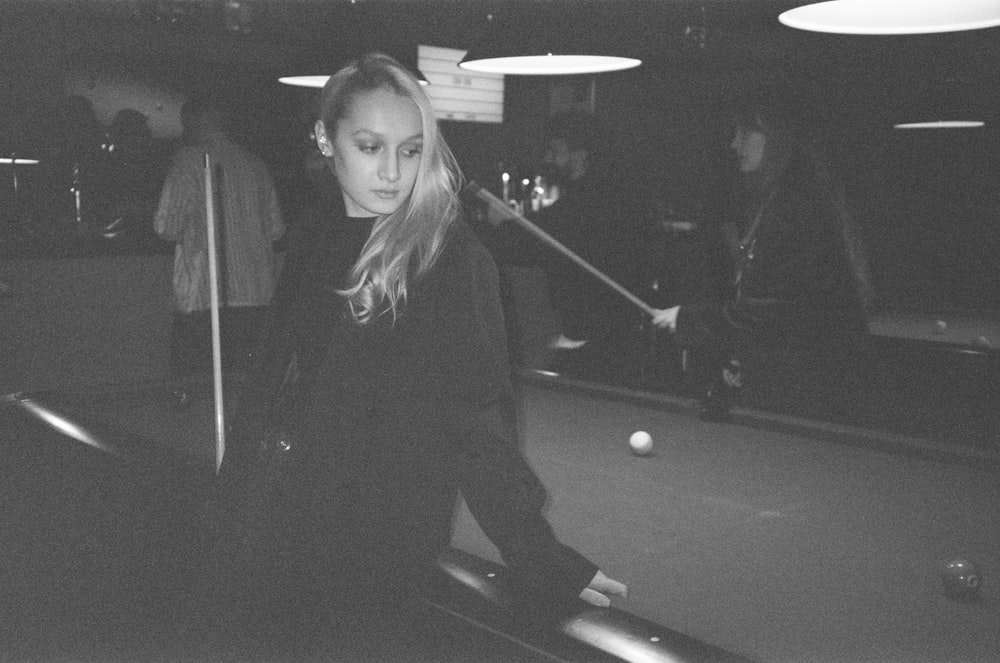 a woman standing next to a pool table