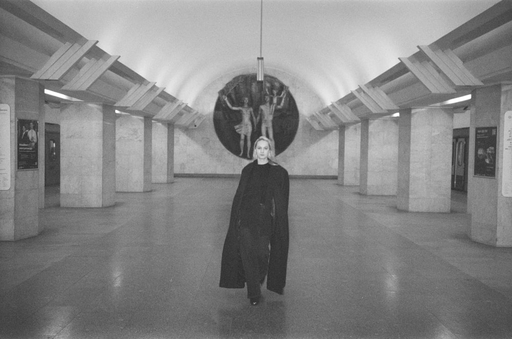 a woman standing in a large room with a clock