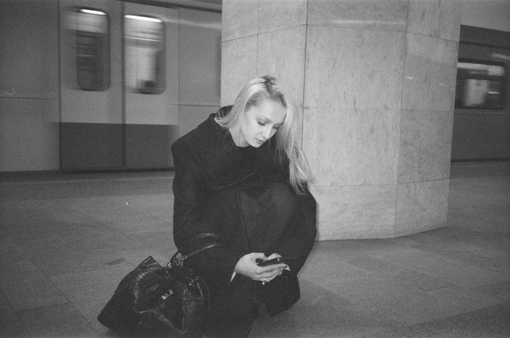 a woman sitting on the ground looking at her cell phone