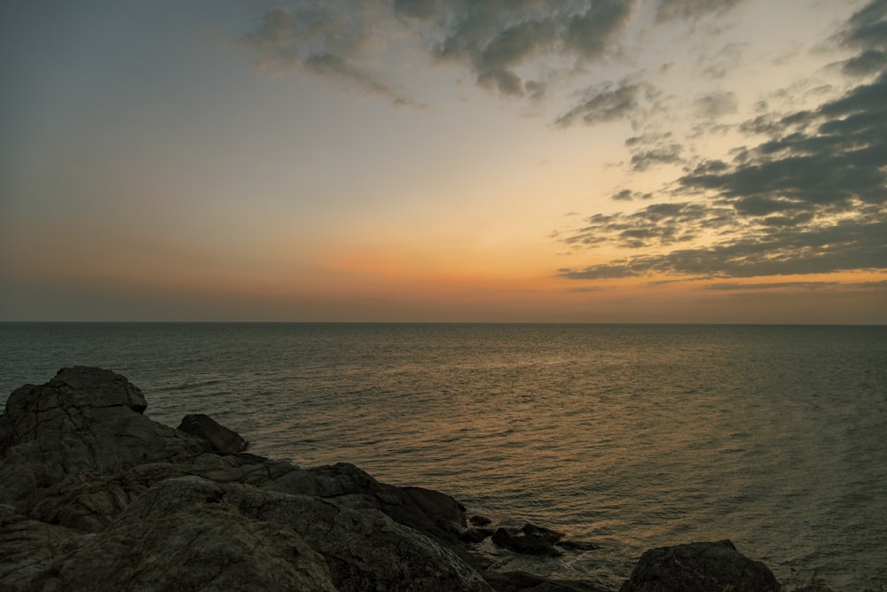 the sun is setting over the ocean on a cloudy day