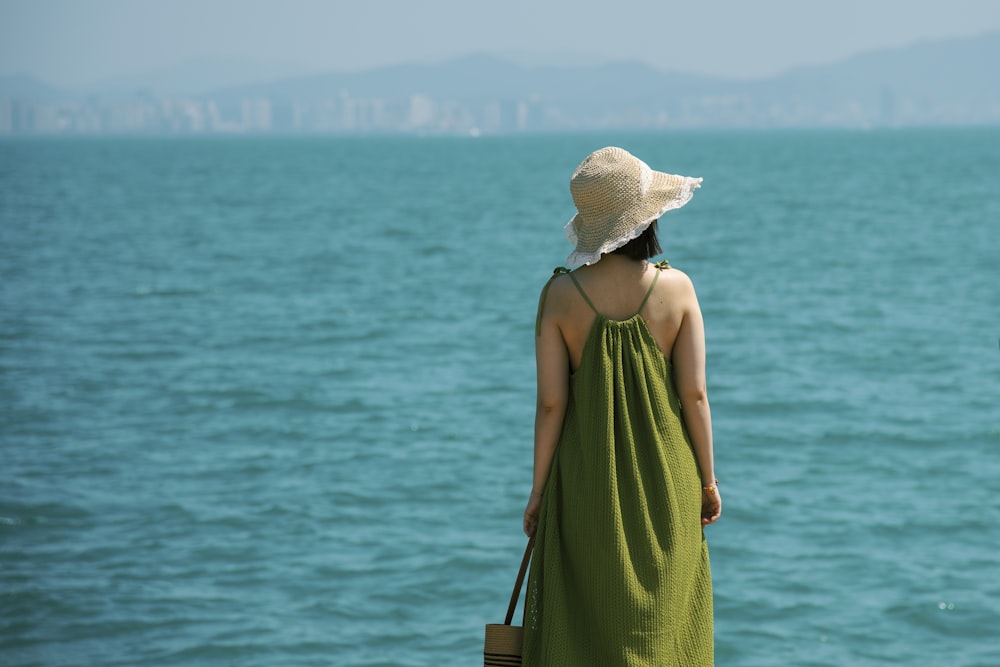 a woman in a green dress looking out at the ocean