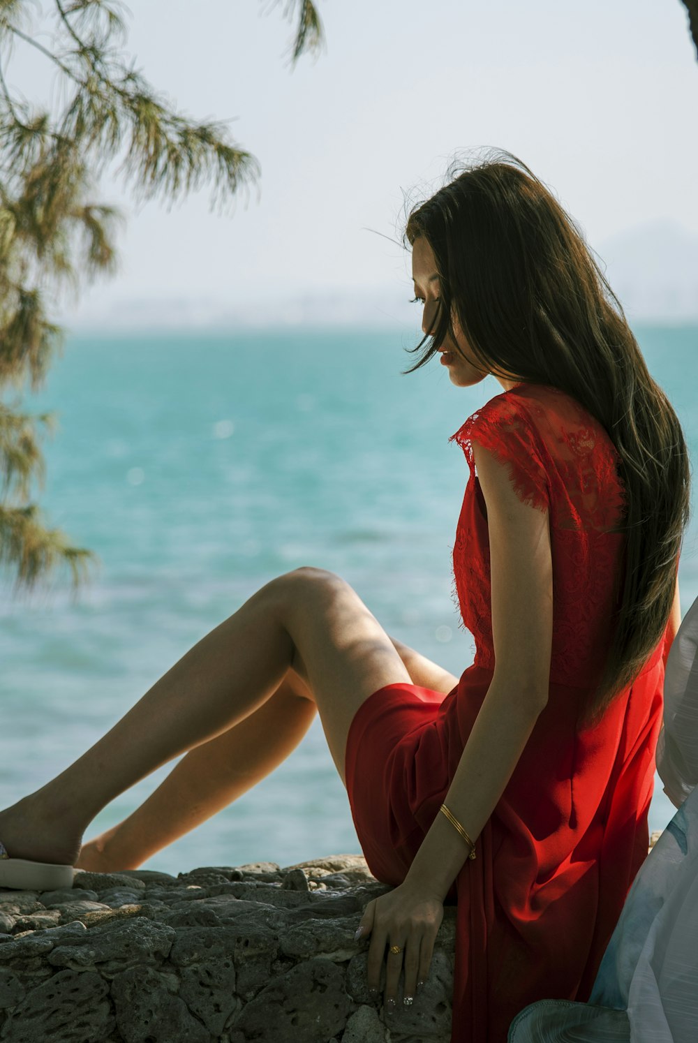 a woman in a red dress sitting on a rock