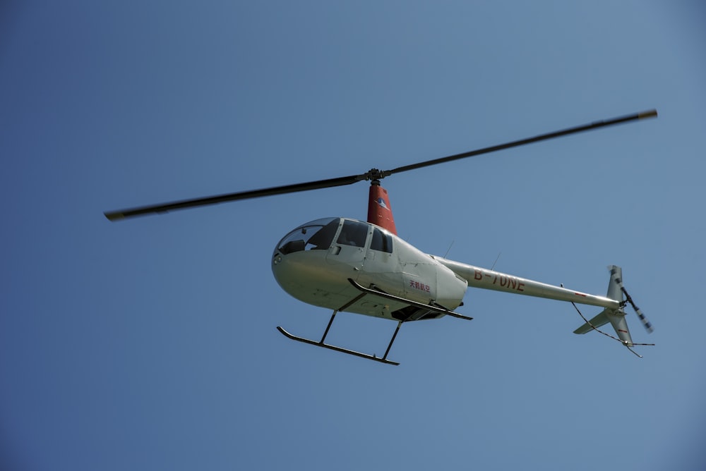 a white helicopter flying through a blue sky