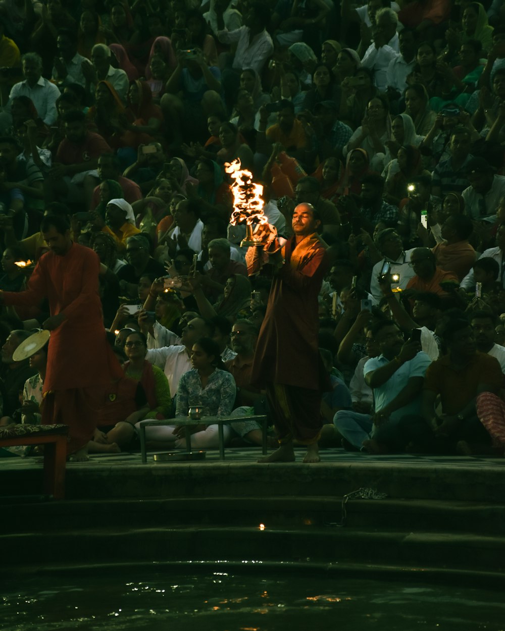 a crowd of people watching a man perform a fire show