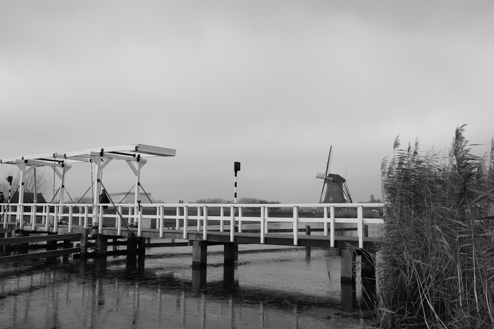 a black and white photo of a bridge and windmill