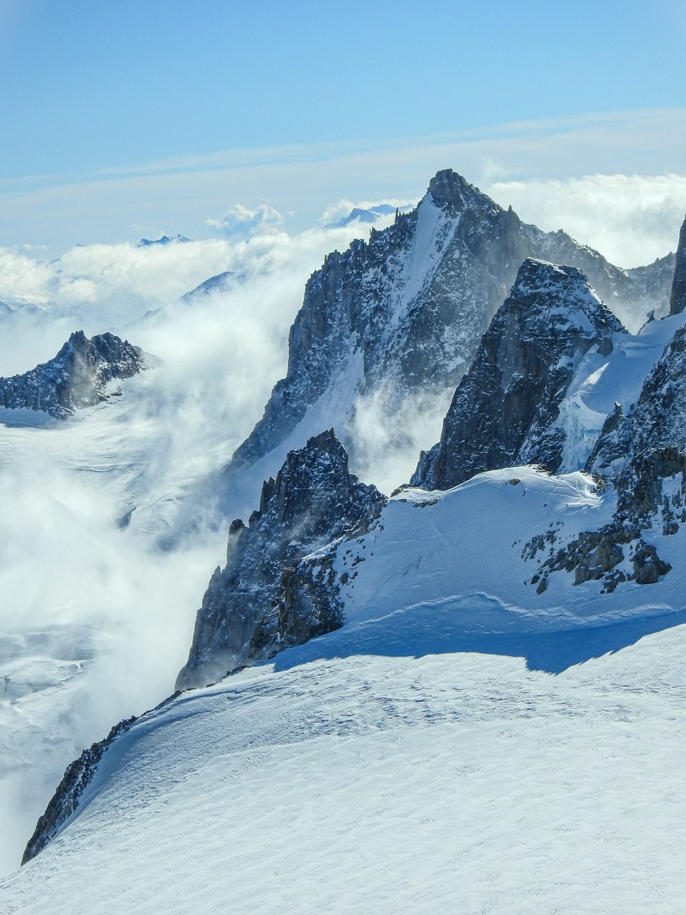 Un hombre montando esquís en la cima de una ladera cubierta de nieve