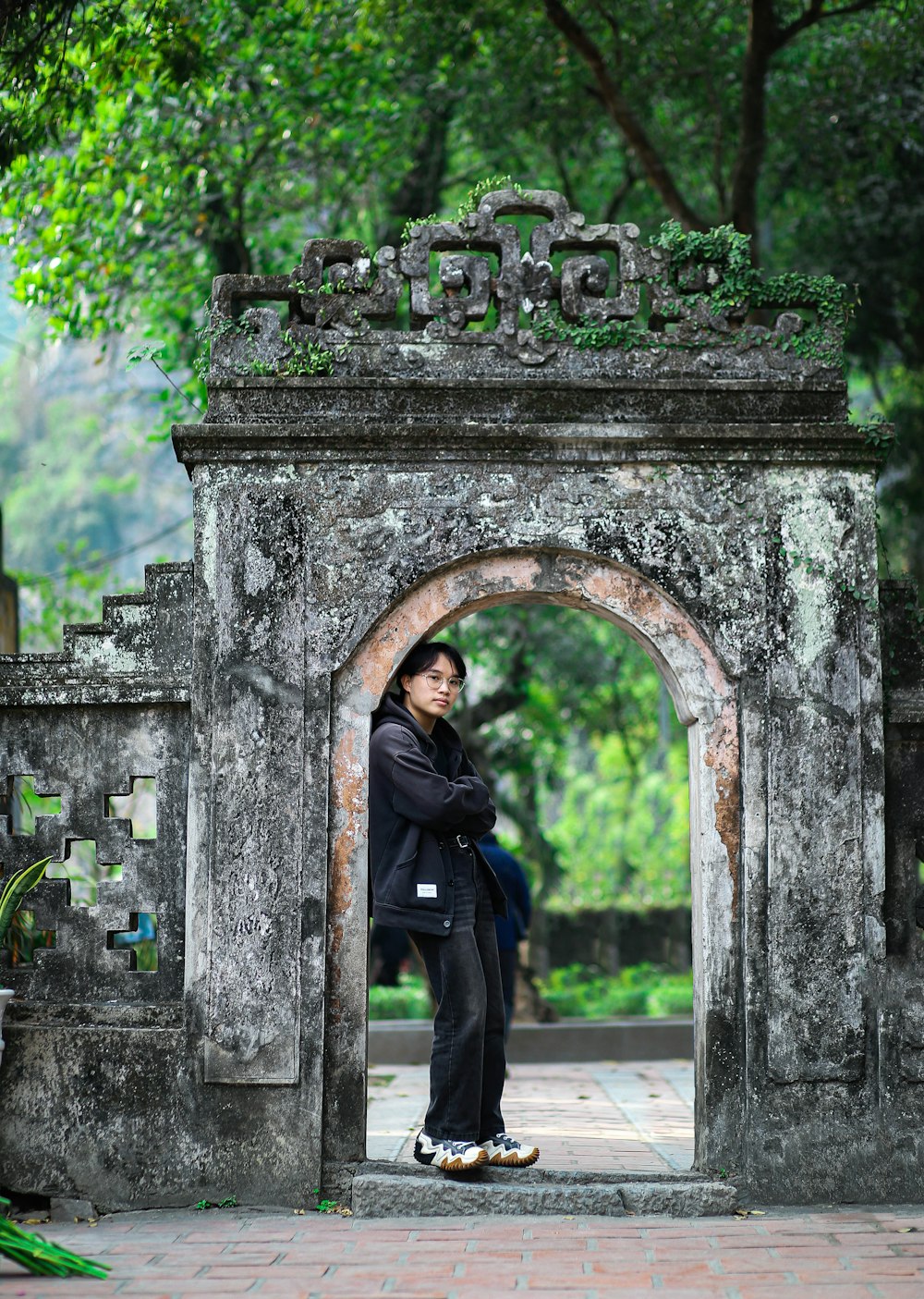 a man standing in a stone archway in a park