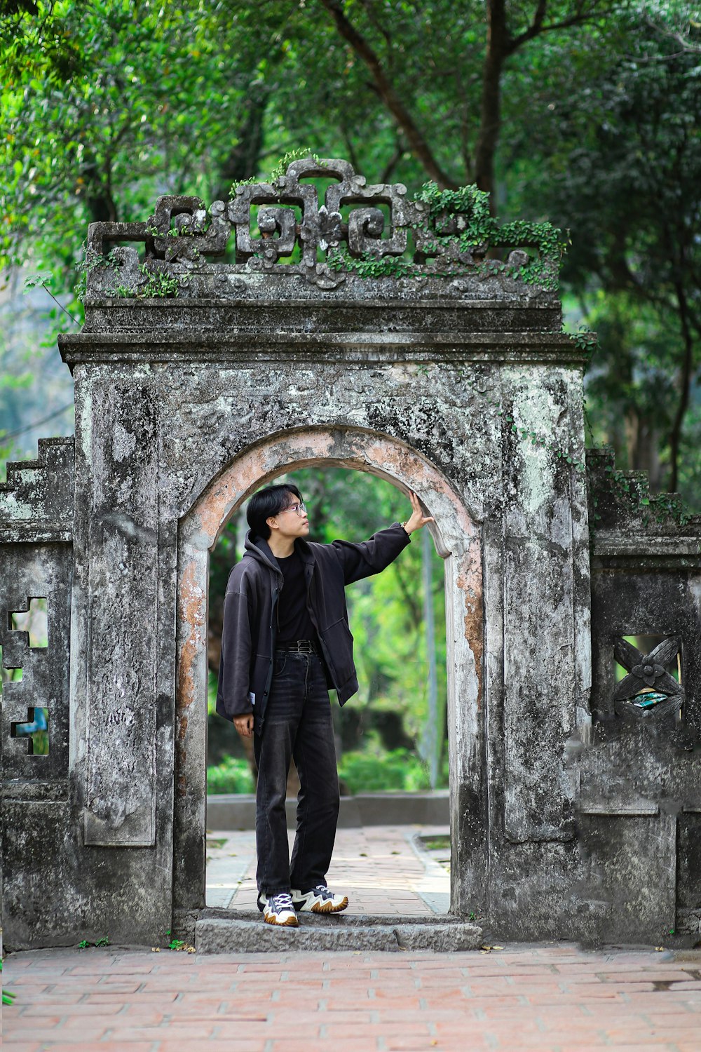 a man standing in front of a stone archway