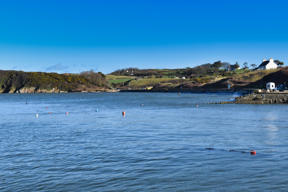 a body of water with a house on a hill in the background