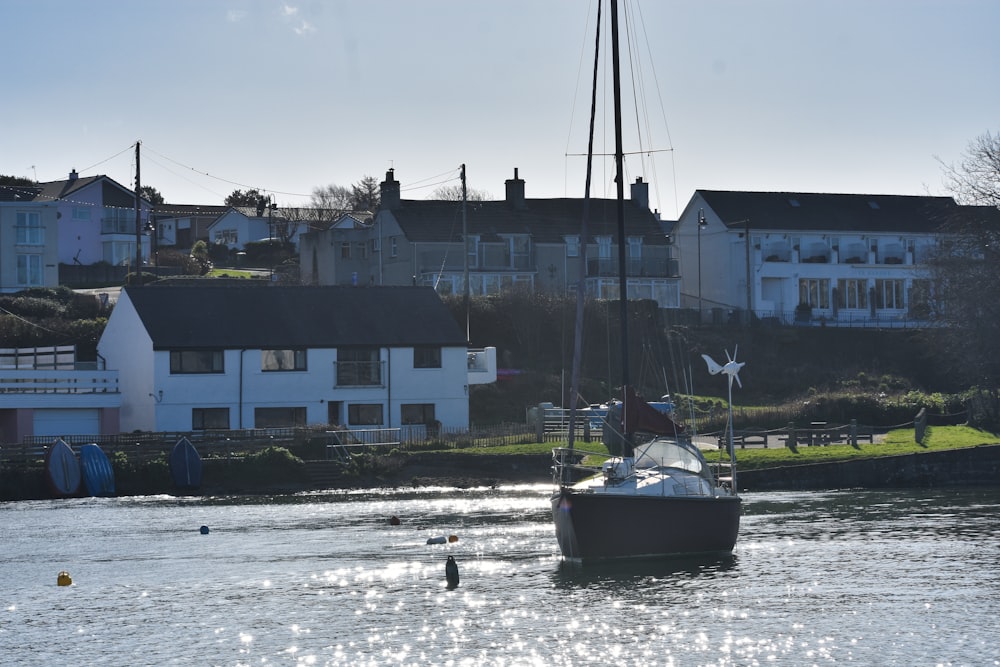 a sailboat in a body of water with houses in the background