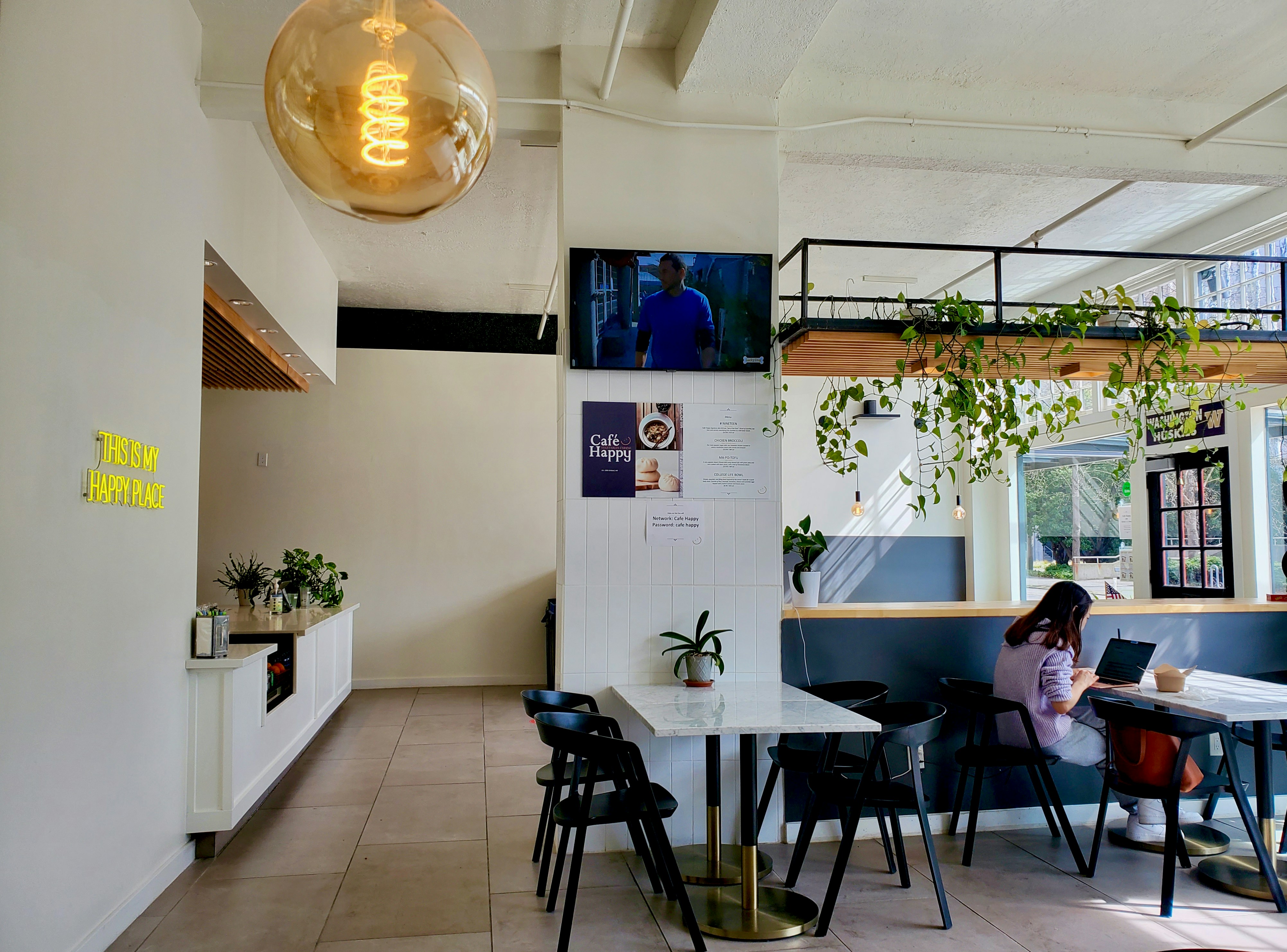 Professional woman working on a laptop in a bright, modern café with large windows overlooking a European street