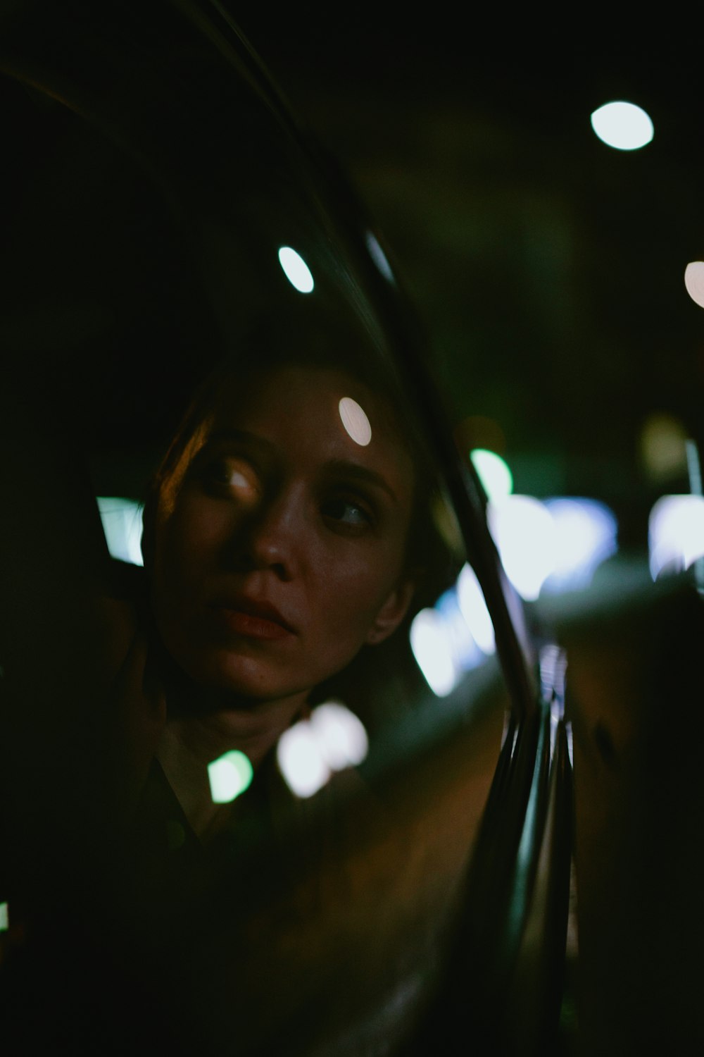 a woman looking out the window of a car at night