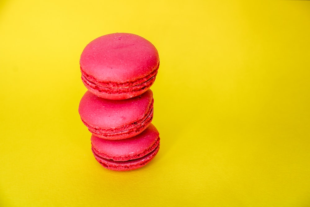 a stack of pink macaroons sitting on top of a yellow table