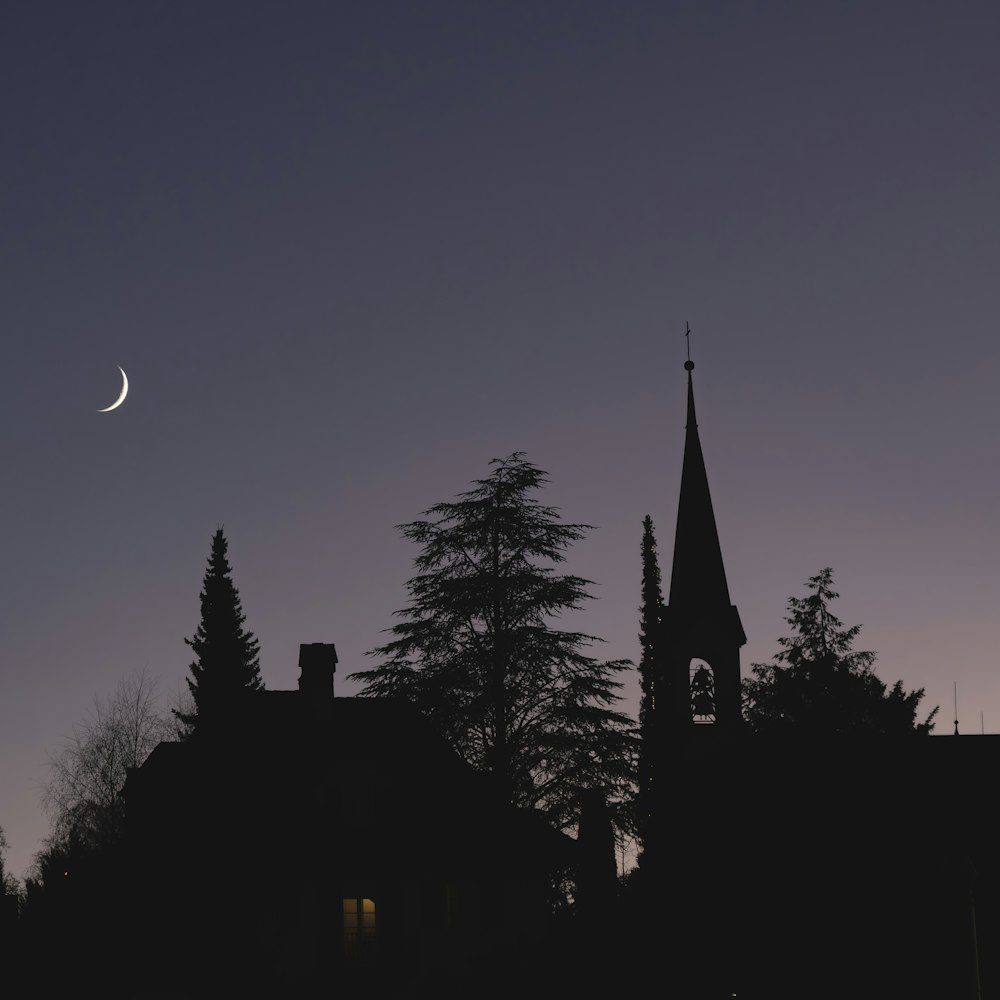 a church steeple with a half moon in the background