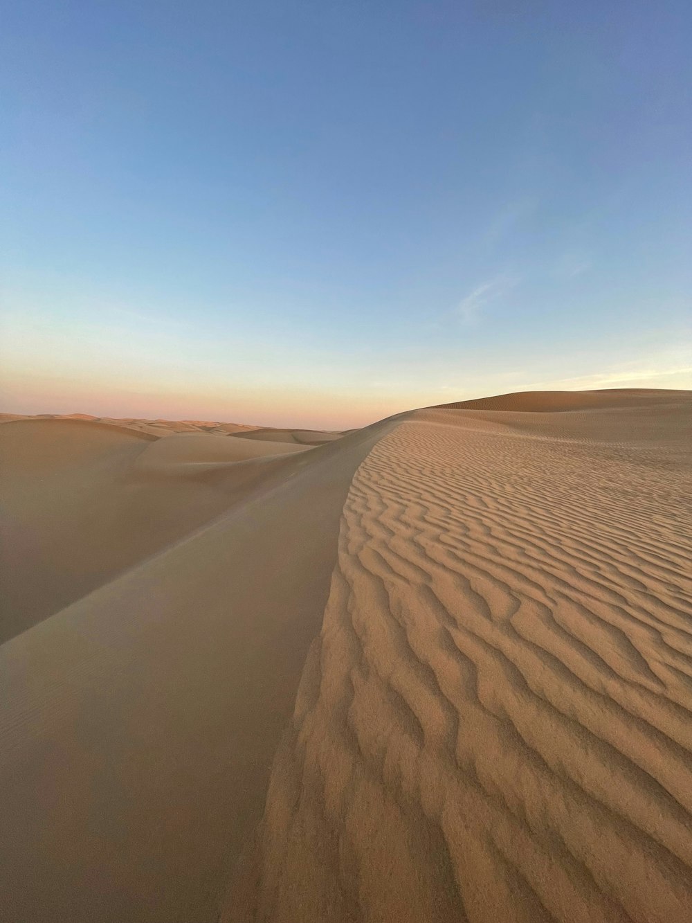 a desert landscape with sand dunes and a blue sky