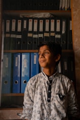 a young boy standing in front of a book shelf