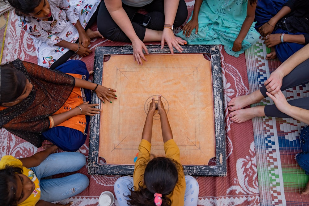 a group of people sitting around a wooden board