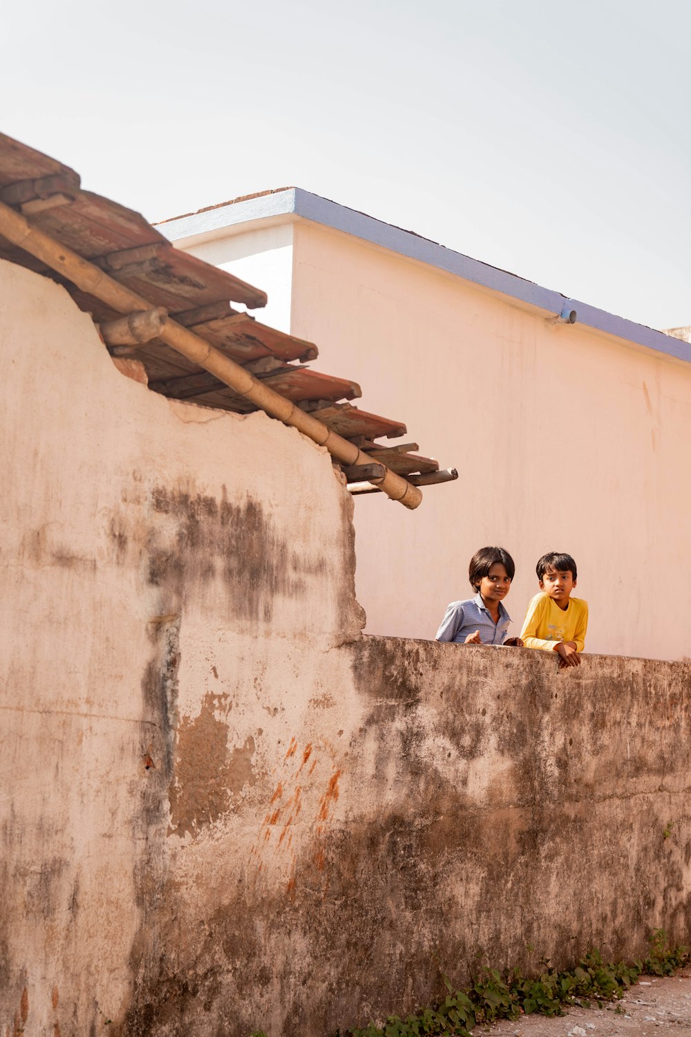 a couple of kids sitting on top of a cement wall