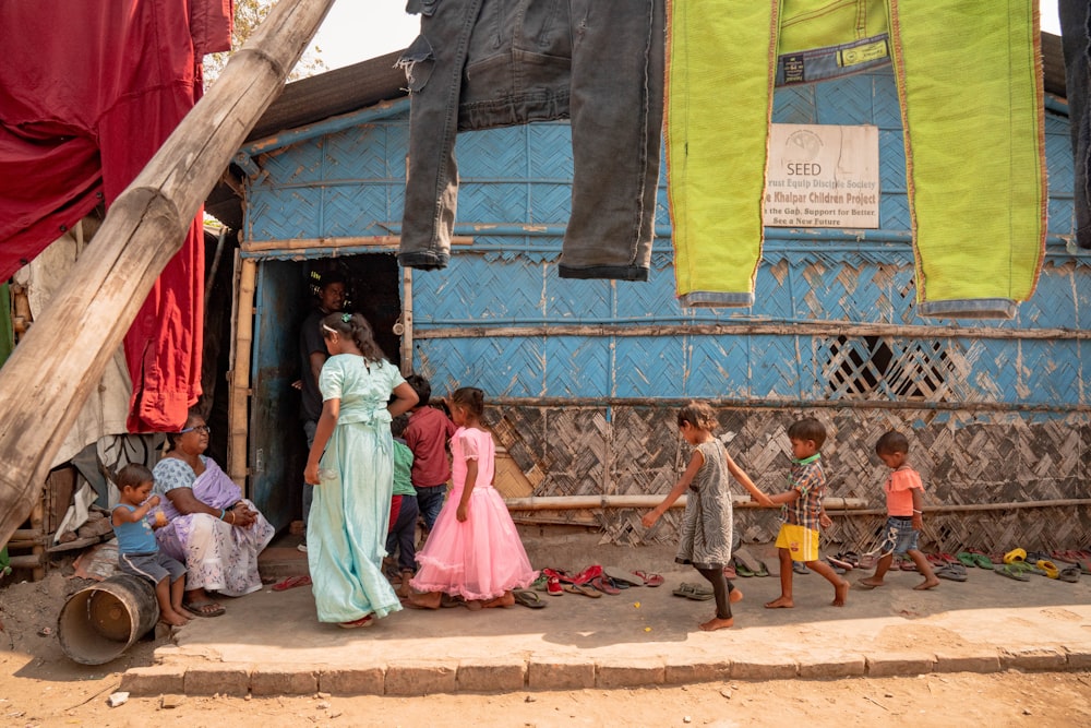 a group of children standing outside of a blue house