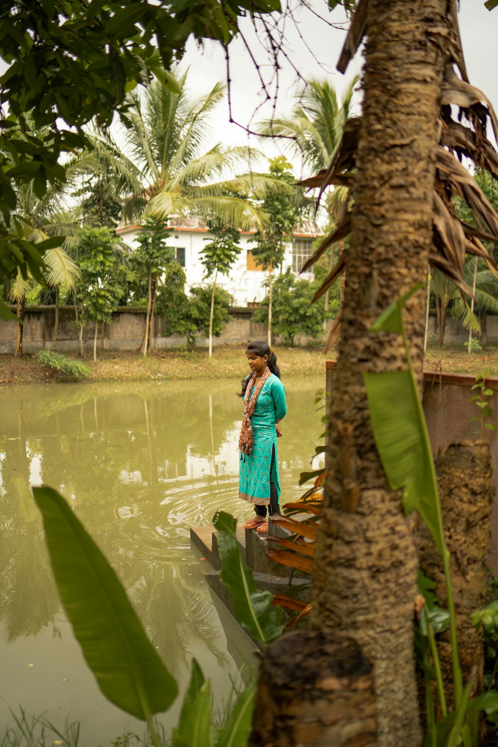 a woman in a blue dress standing on a dock