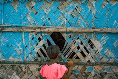 a little girl standing in front of a blue wall