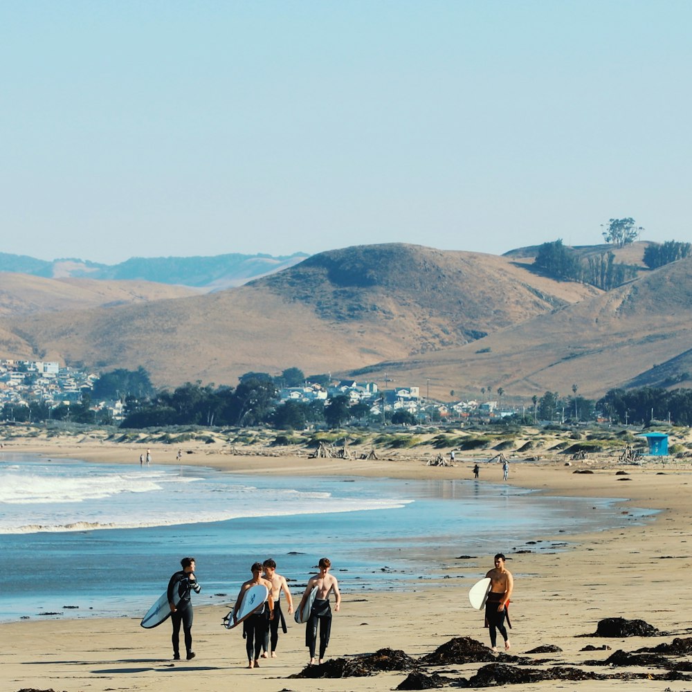 a group of people walking on top of a sandy beach