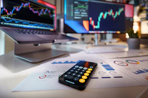 smartphone calculator on desk with financial charts behind