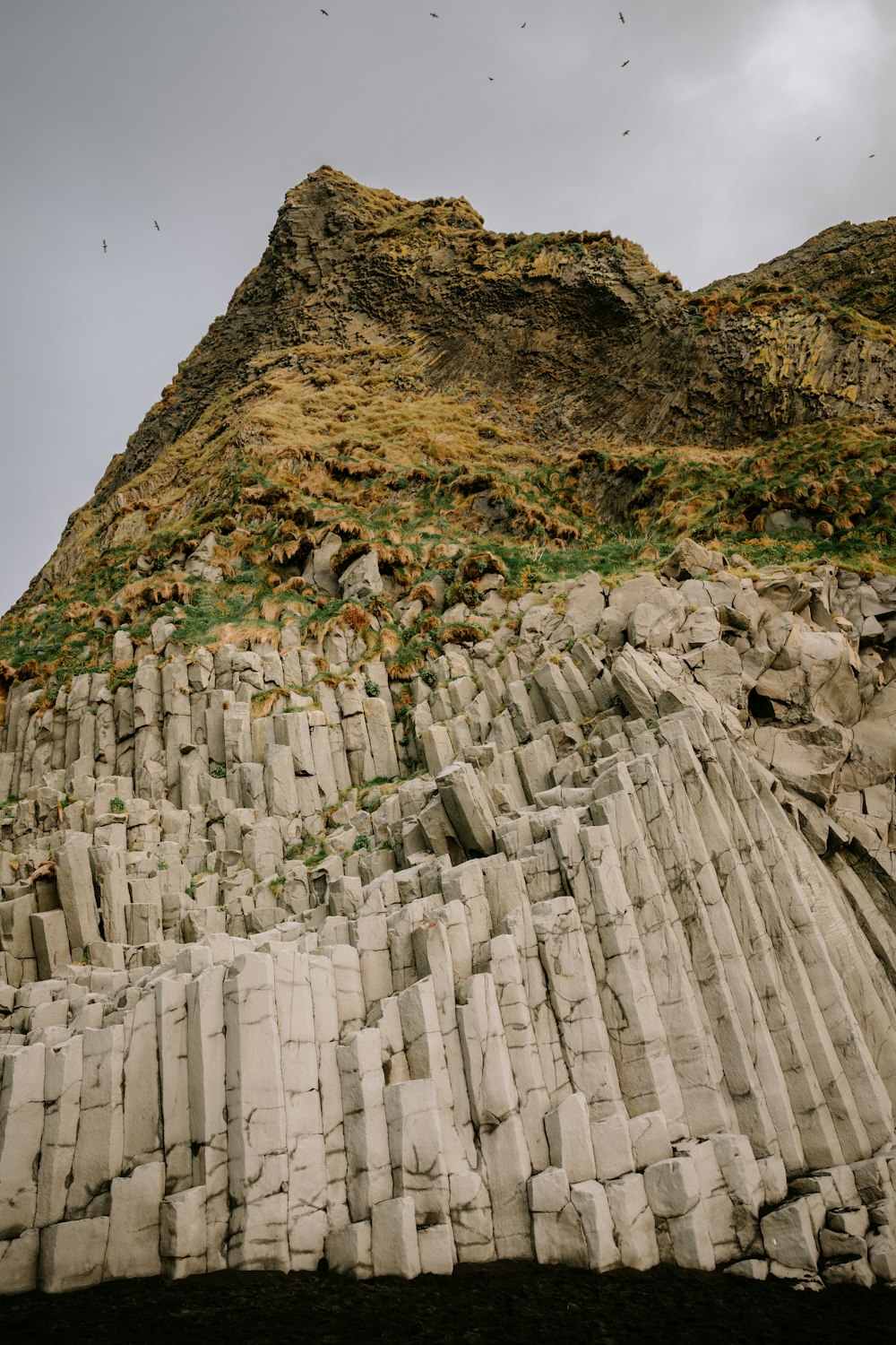 a large rock formation with birds flying over it