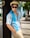 a man leaning against a tree wearing a hat and sunglasses