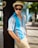 a man leaning against a tree wearing a hat and sunglasses