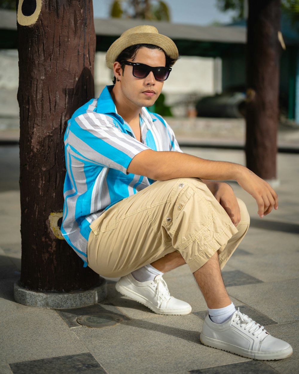 a man sitting on the ground next to a tree