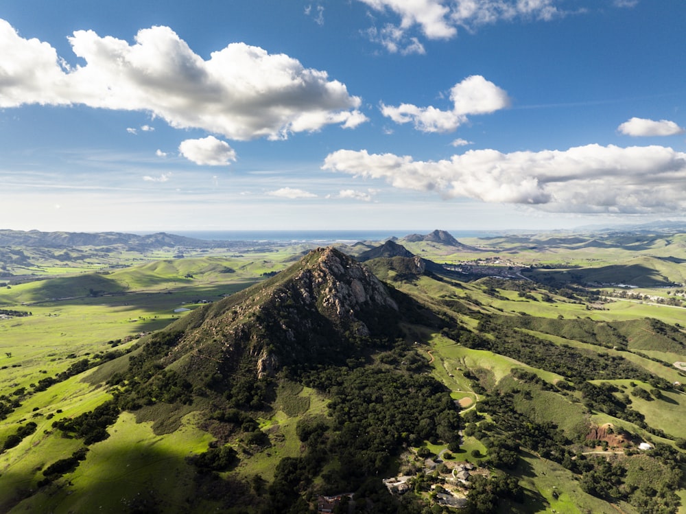 an aerial view of a mountain with green fields and trees