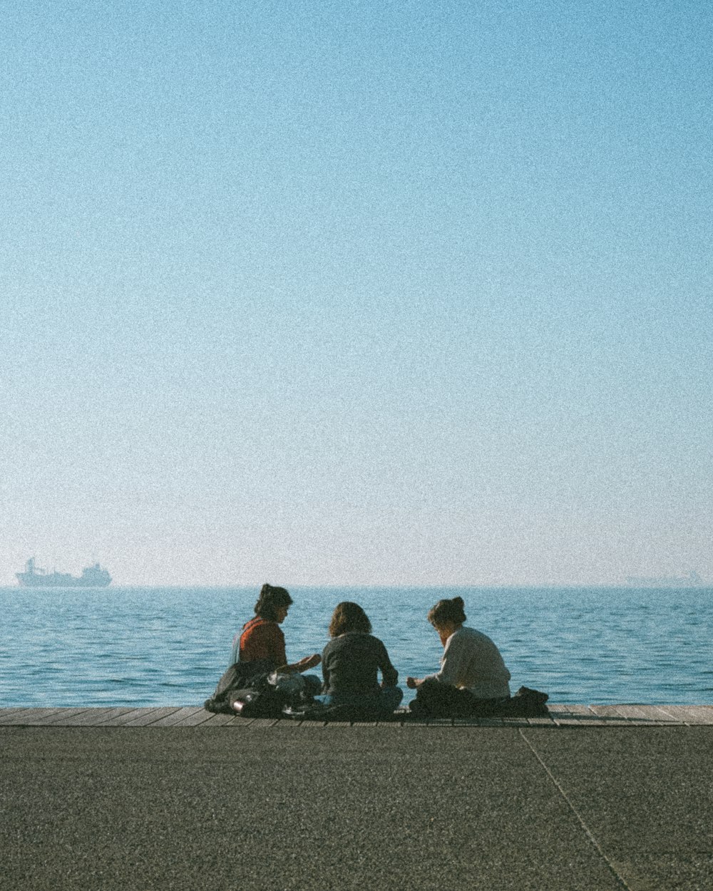 a group of people sitting on top of a pier next to the ocean