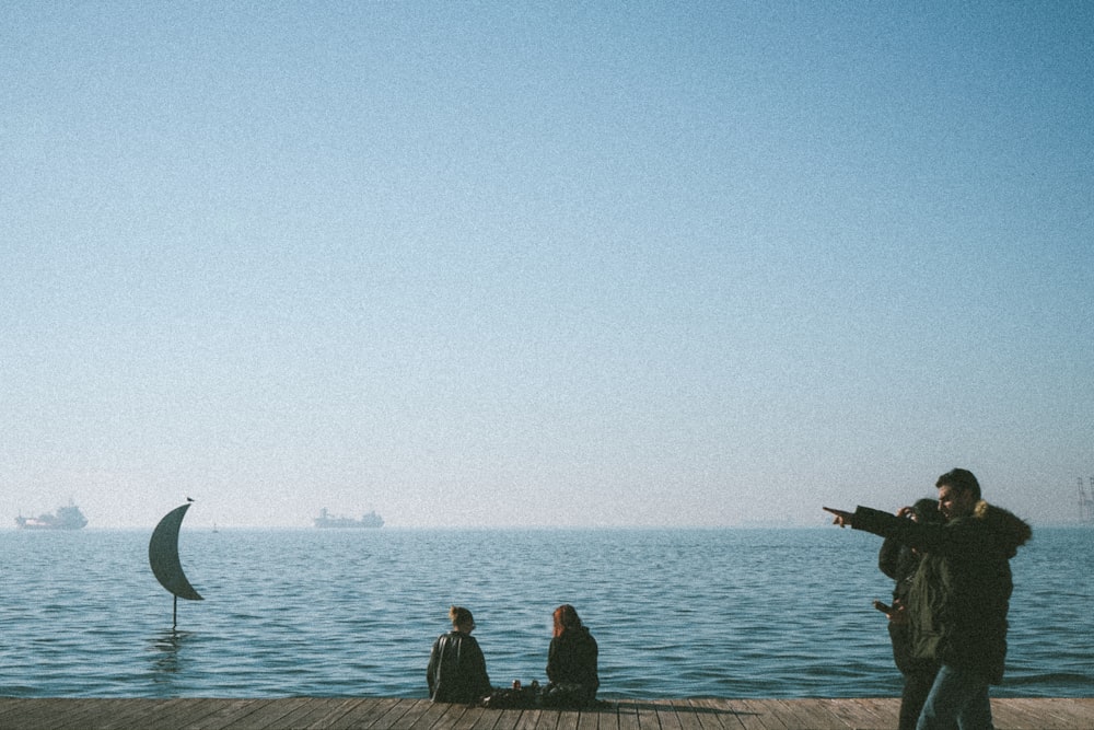 a group of people standing on top of a wooden pier