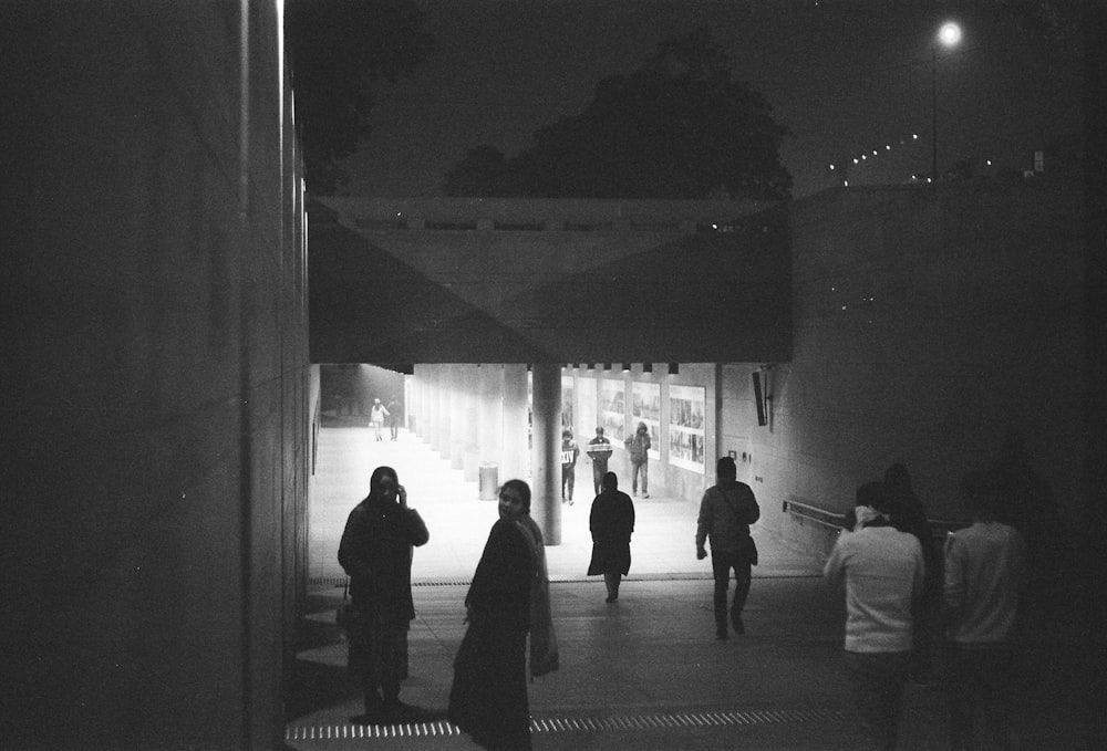 a group of people standing outside of a building at night