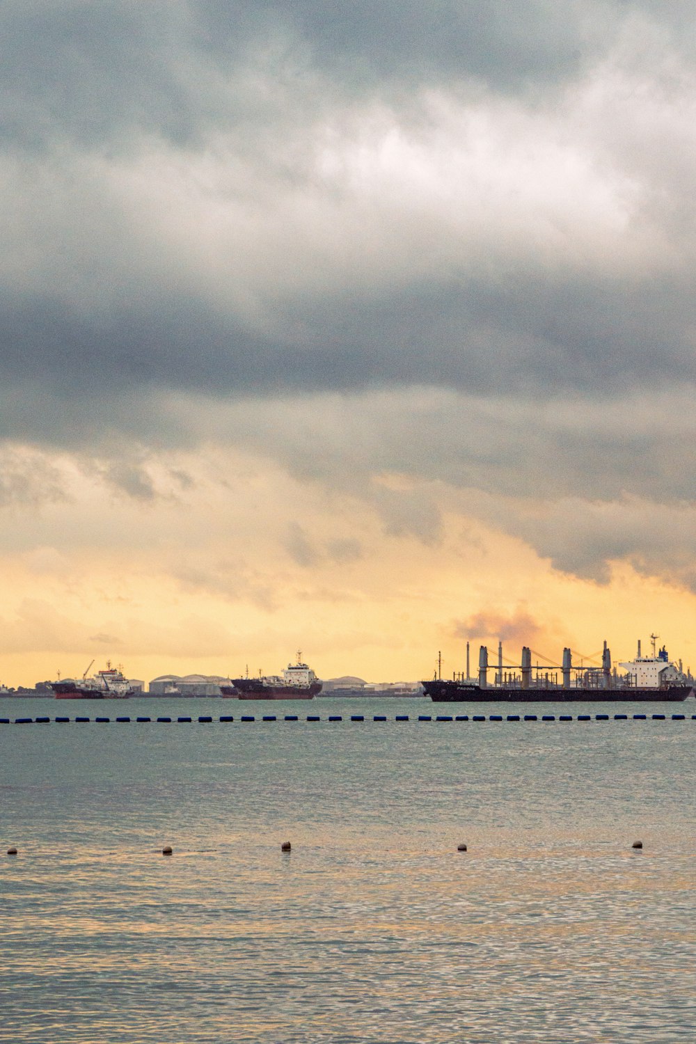 a large cargo ship in the distance under a cloudy sky