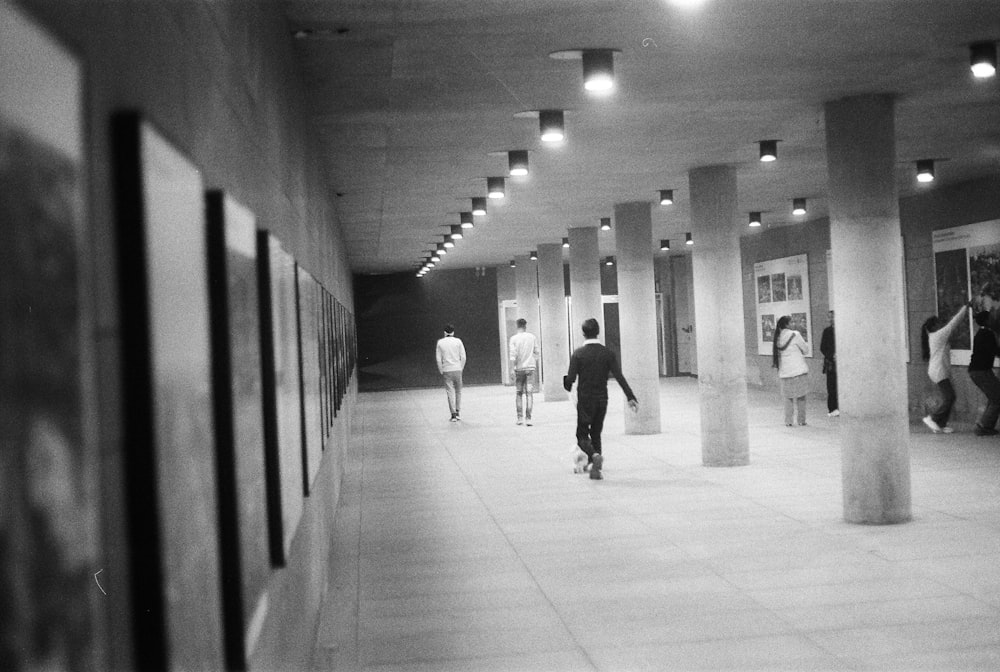 a black and white photo of people walking down a hallway