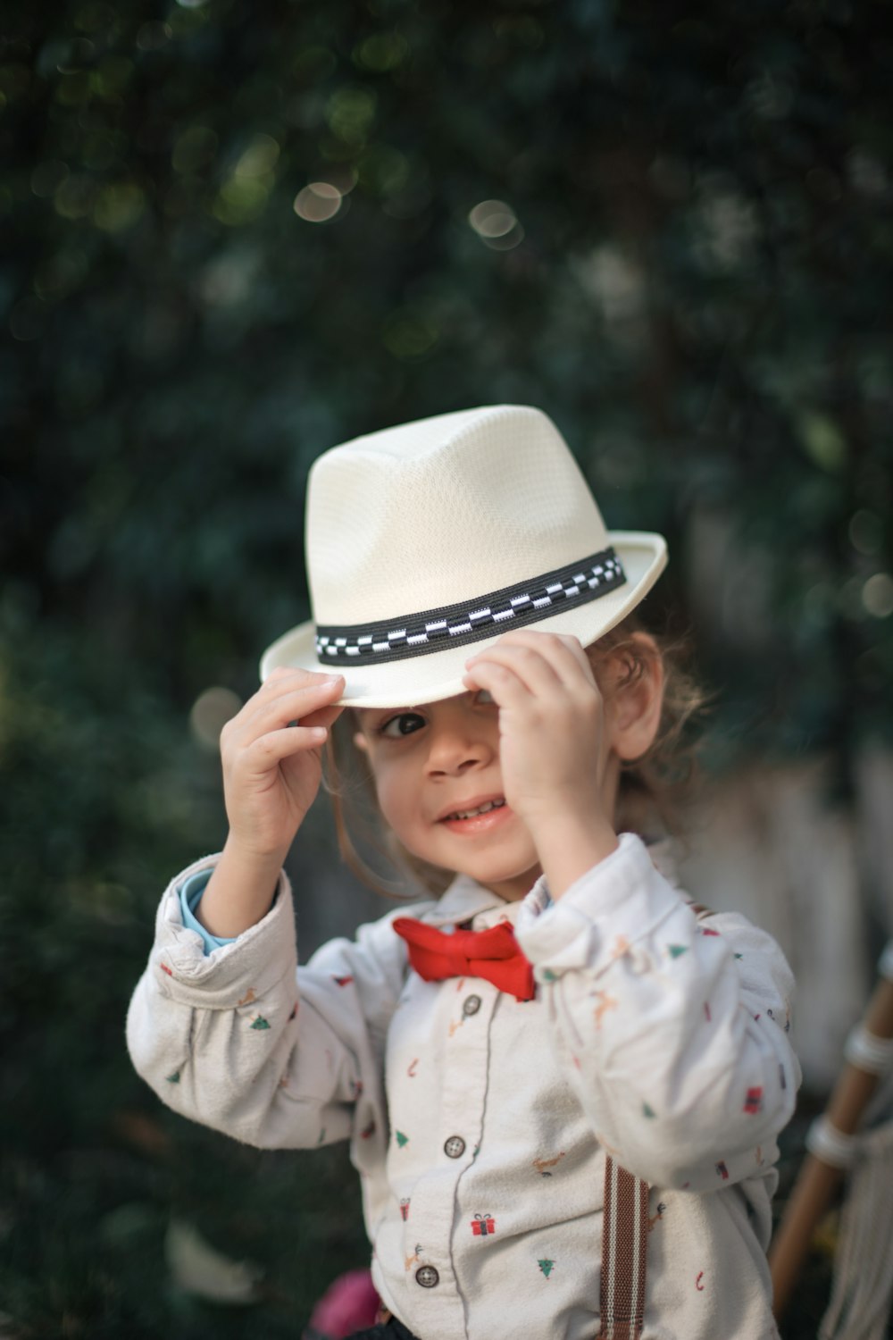 a little girl wearing a white hat and bow tie