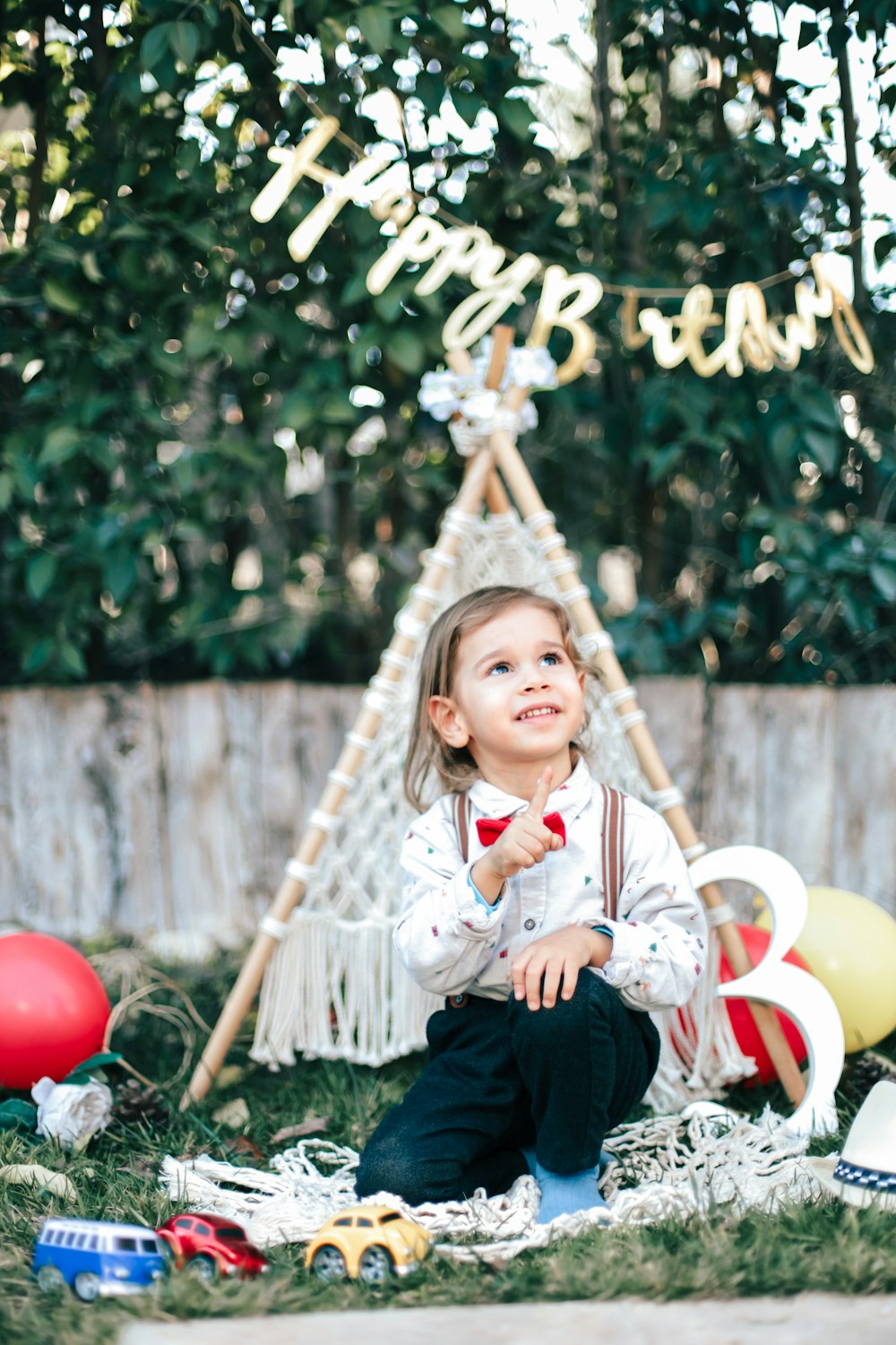 a little girl sitting on the ground in front of a teepee tent