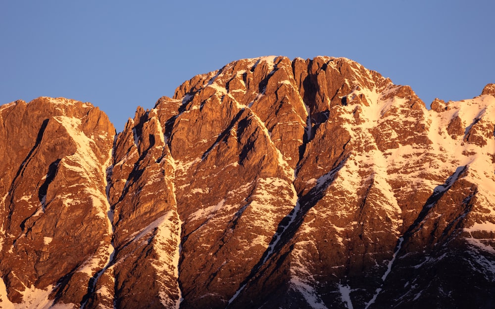 a very tall mountain covered in snow under a blue sky