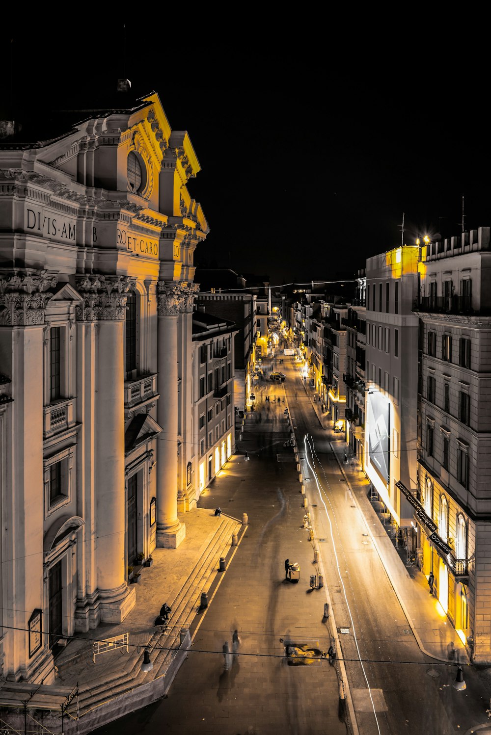 a city street at night with people walking on it