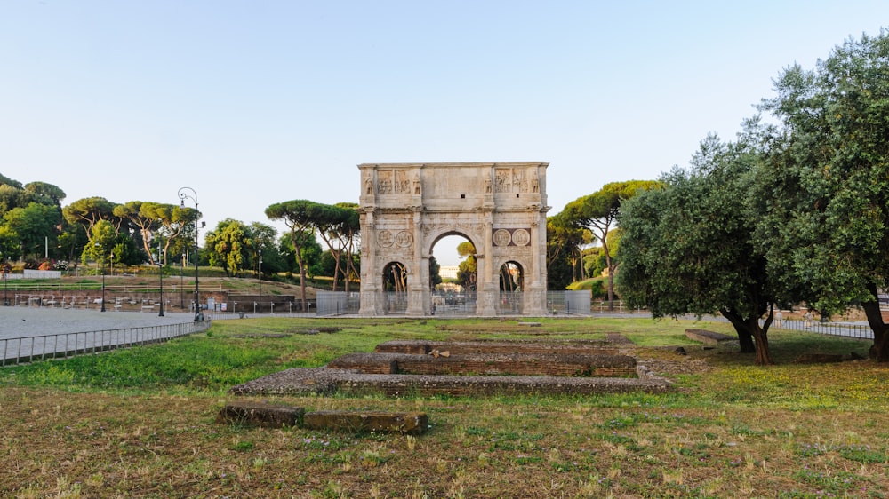 a stone arch in a park with trees around it