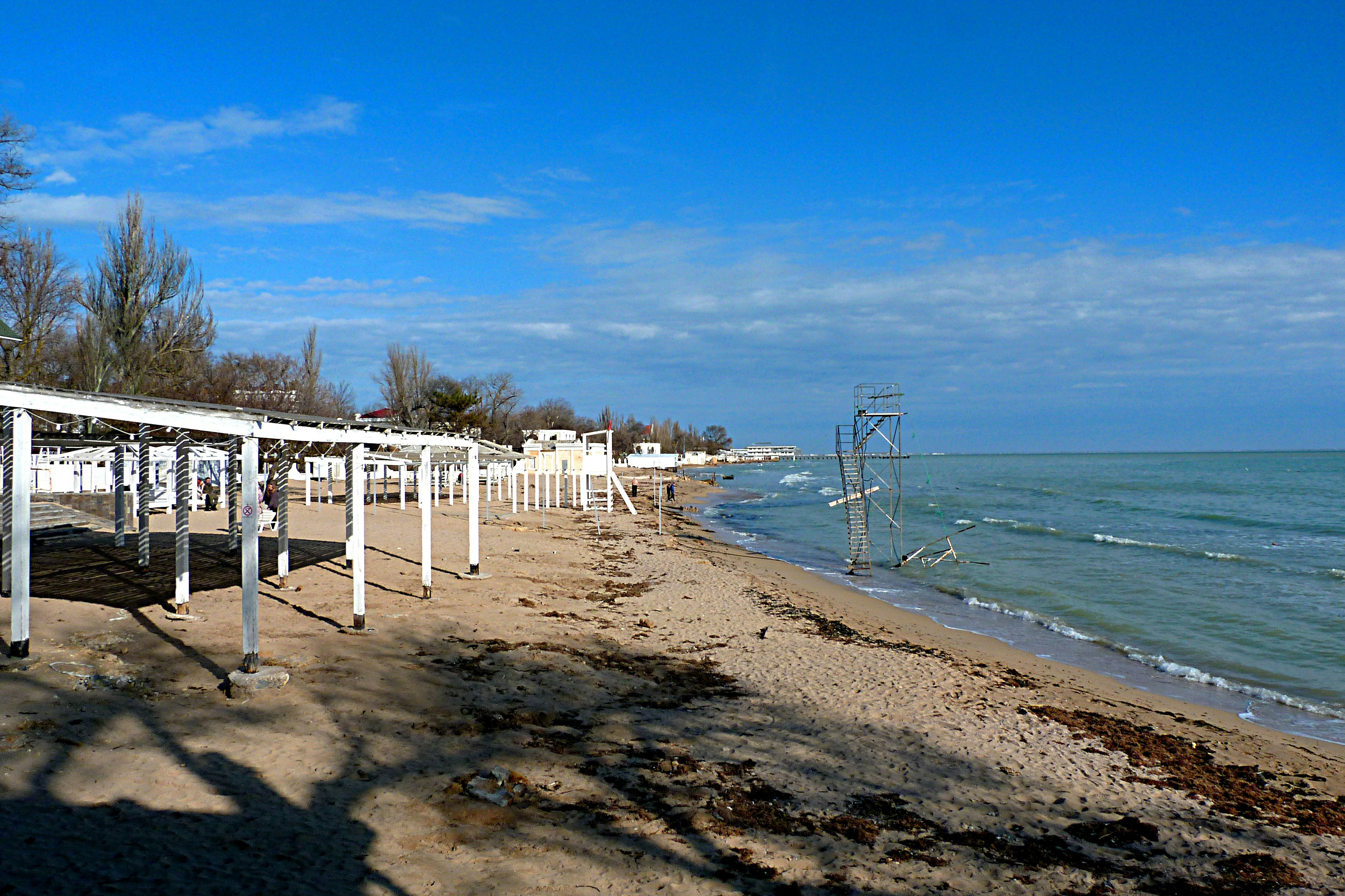 a row of white benches sitting on top of a sandy beach