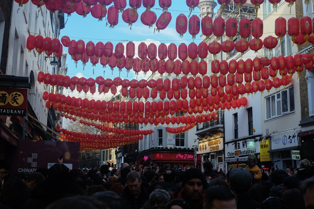 a crowd of people walking down a street under red lanterns