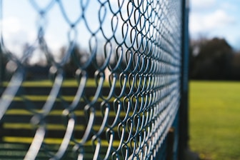 a close up of a metal fence with grass in the background