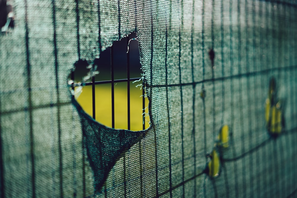 a close up of a metal fence with a hole in it