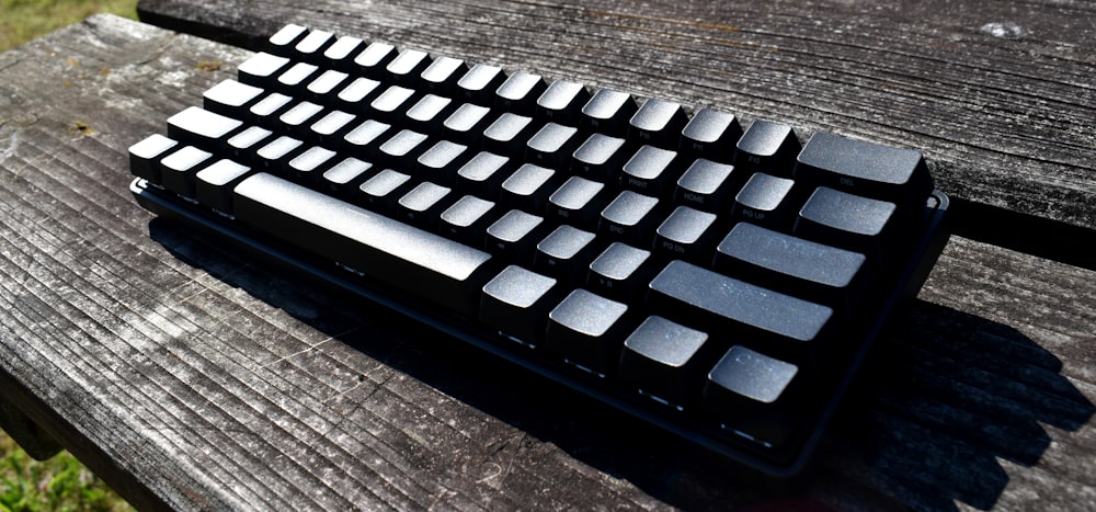 a computer keyboard sitting on top of a wooden table