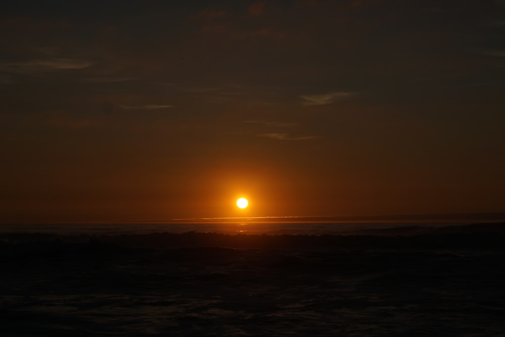 O sol está se pondo sobre o oceano em um dia nublado