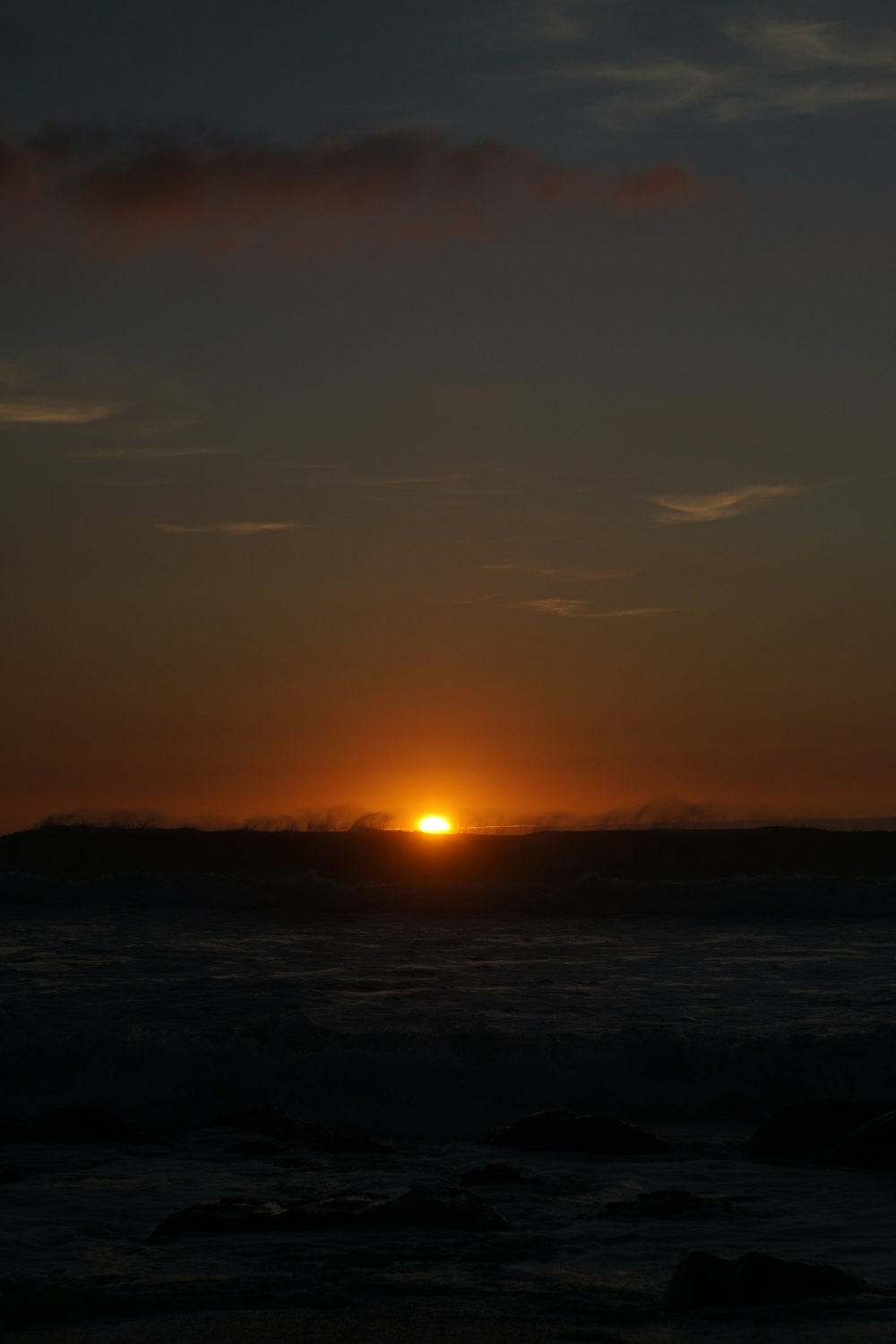 O sol está se pondo sobre o oceano em um dia nublado