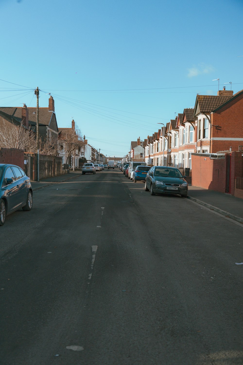 cars parked on the side of a road next to a row of houses